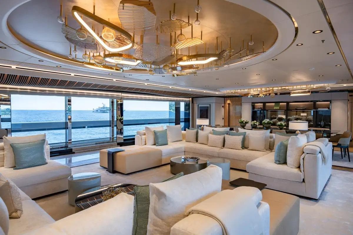 Superyacht main saloon interior with curved seating and statement lighting, the standard of presentation international buyers expect