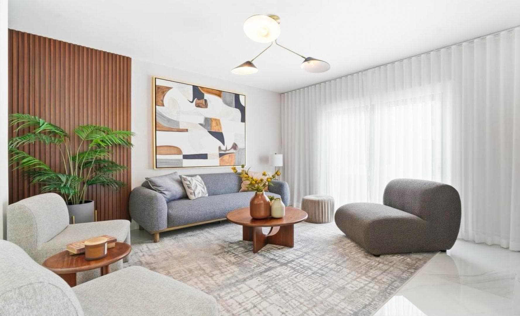 Living room interior with grey sofa, round wood coffee table and curved accent chairs